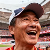 一位中年男性球迷的头像照片，他戴着棒球帽，背景是北京工人体育场的看台，表情热情洋溢